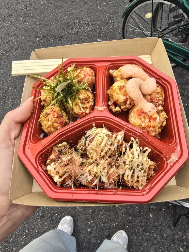 plato de takoyaki (bolitas de masa rellenas de pulpo) surtido con diferentes aderezos, servido en una bandeja roja dividida