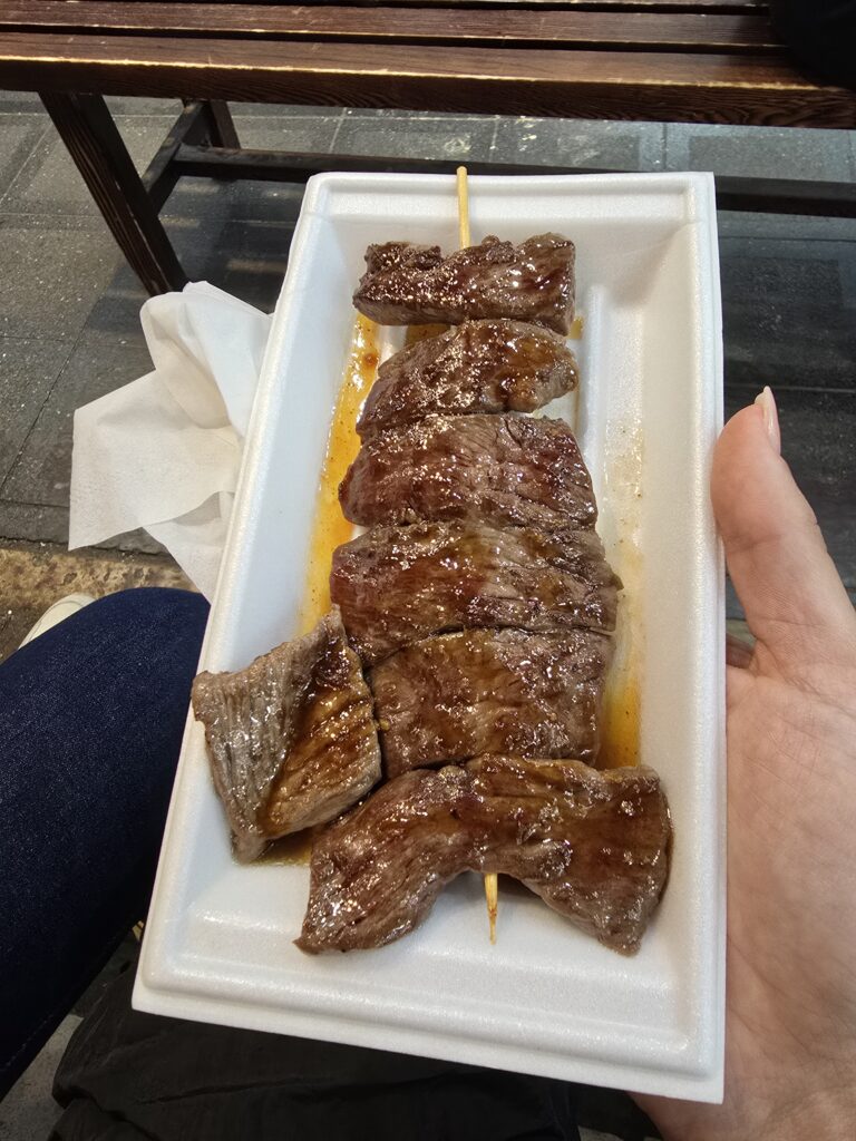 brocheta de carne Wagyu o buey de Kobe, uno de los bocados de comida callejera (conocido genéricamente como kushiyaki o gyukushi) más icónicos y populares de los mercados tradicionales en Japón.