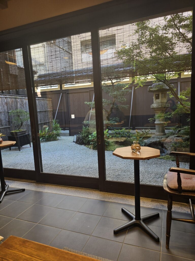 interior de un ryokan tradicional japonés con vistas a un pequeño jardín de piedra y una linterna de piedra (toro) exterior.