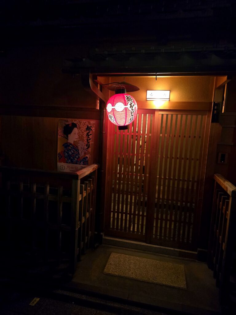 entrada tradicional de un establecimiento japonés con una linterna roja redonda (chochin) y una puerta corredera de madera de celosía (koshi-do)
