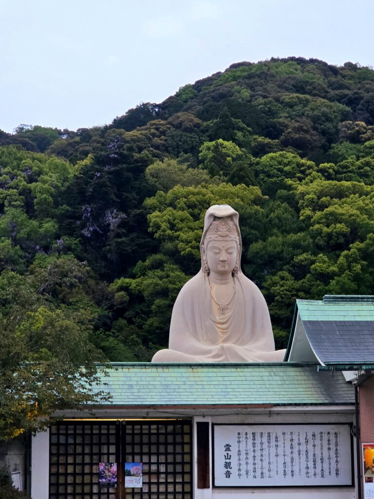 Monumento y templo de Ryozen Kannon frente a una colina arbolada en el distrito histórico de Higashiyama, Kioto.