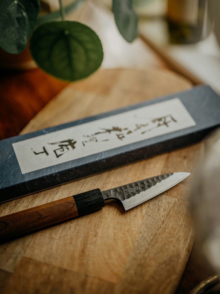 cuchillo utilitario japonés tipo petty o ko-deba con acabado martillado (tsuchime) y un mango tradicional de madera.
