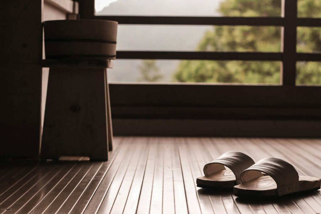zapatillas tradicionales japonesas sobre un suelo de listones de madera en un balcón o pasillo de estilo tradicional (ryokan).