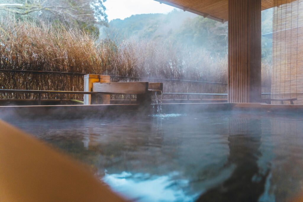 Onsen , un baño de aguas termales tradicionales al aire libre en Japón, con vapor elevándose sobre el agua
