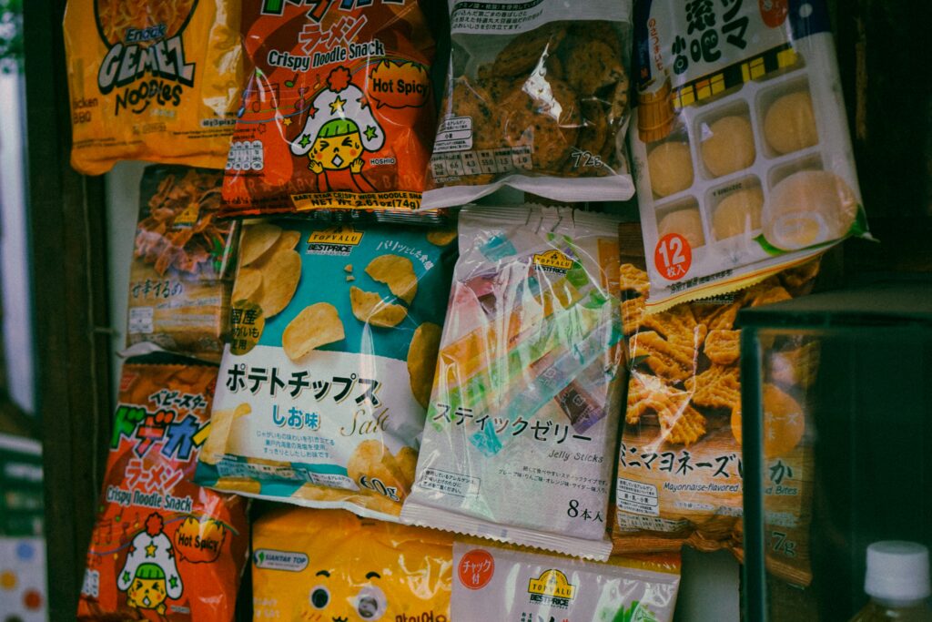 snacks japoneses en un estante, incluyendo bolsitas de fideos crujientes estilo Baby Star y patatas fritas.
